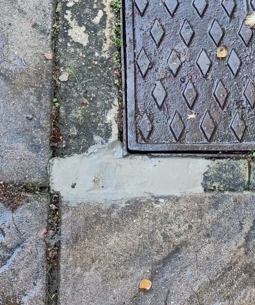 Freshly laid concrete to make good a missing section that we found around a sewer manhole cover