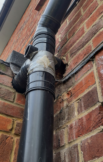 A sewer pipe junction held together with tape