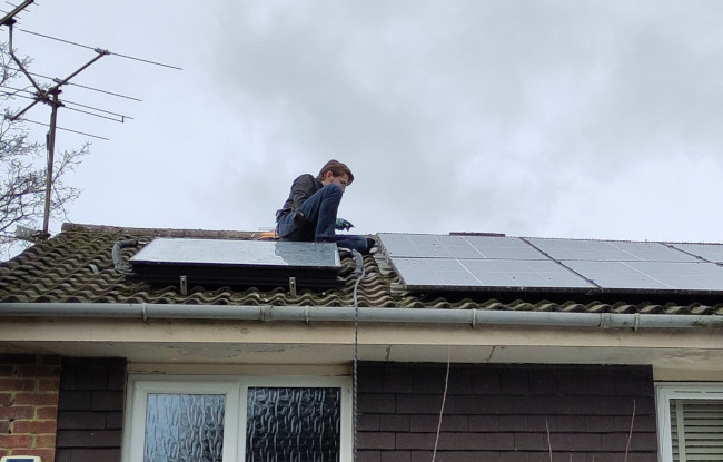 Attaching mesh to PV solar panels on a home with a water heater panel also installed